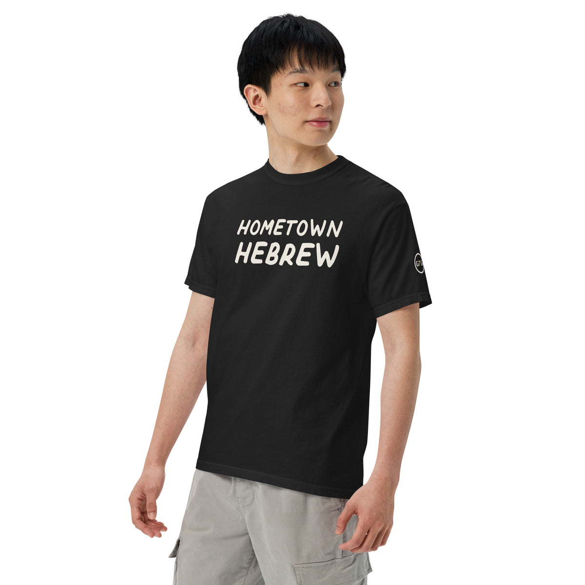 Model wearing the Good Thank God Hometown Hebrew T-shirt in Black, left front view showing the GTG sleeve badge