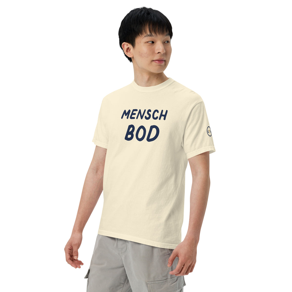 Model wearing the Good Thank God Mensch Bod T-shirt in Ivory, left front view showing the GTG sleeve badge
